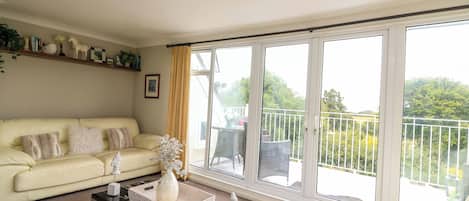 A spacious living room with a large sliding glass door leading to a balcony.