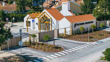 A modern building with a white facade and orange roof, featuring a pedestrian entrance and a sign reading 'PESTA NA COMPORTA'.