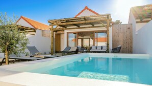 Une piscine avec des chaises longues, une pergola et une clôture en bois.