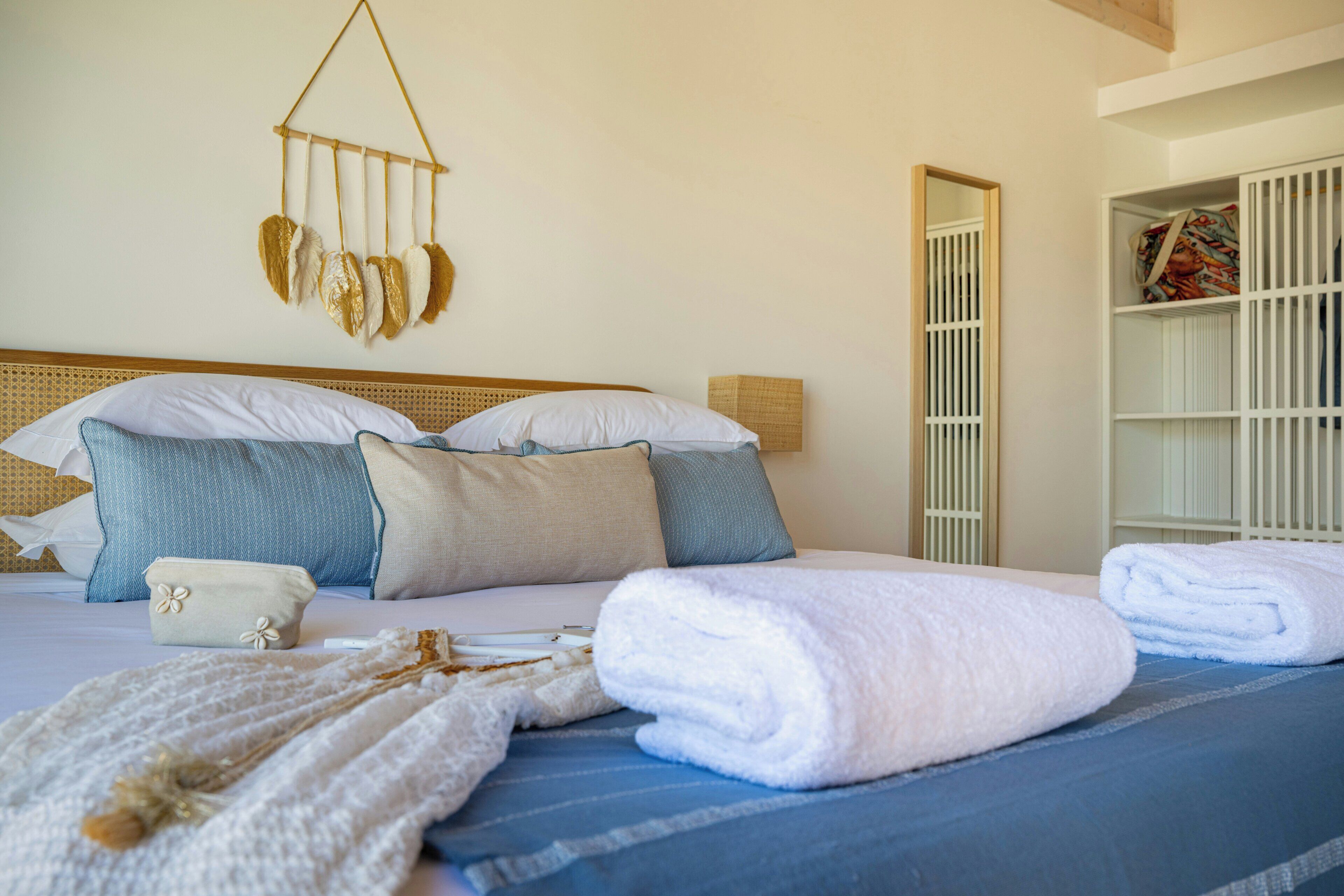 A neatly made bed with a blue and white striped bedspread, a white pillow, and a decorative wall hanging.