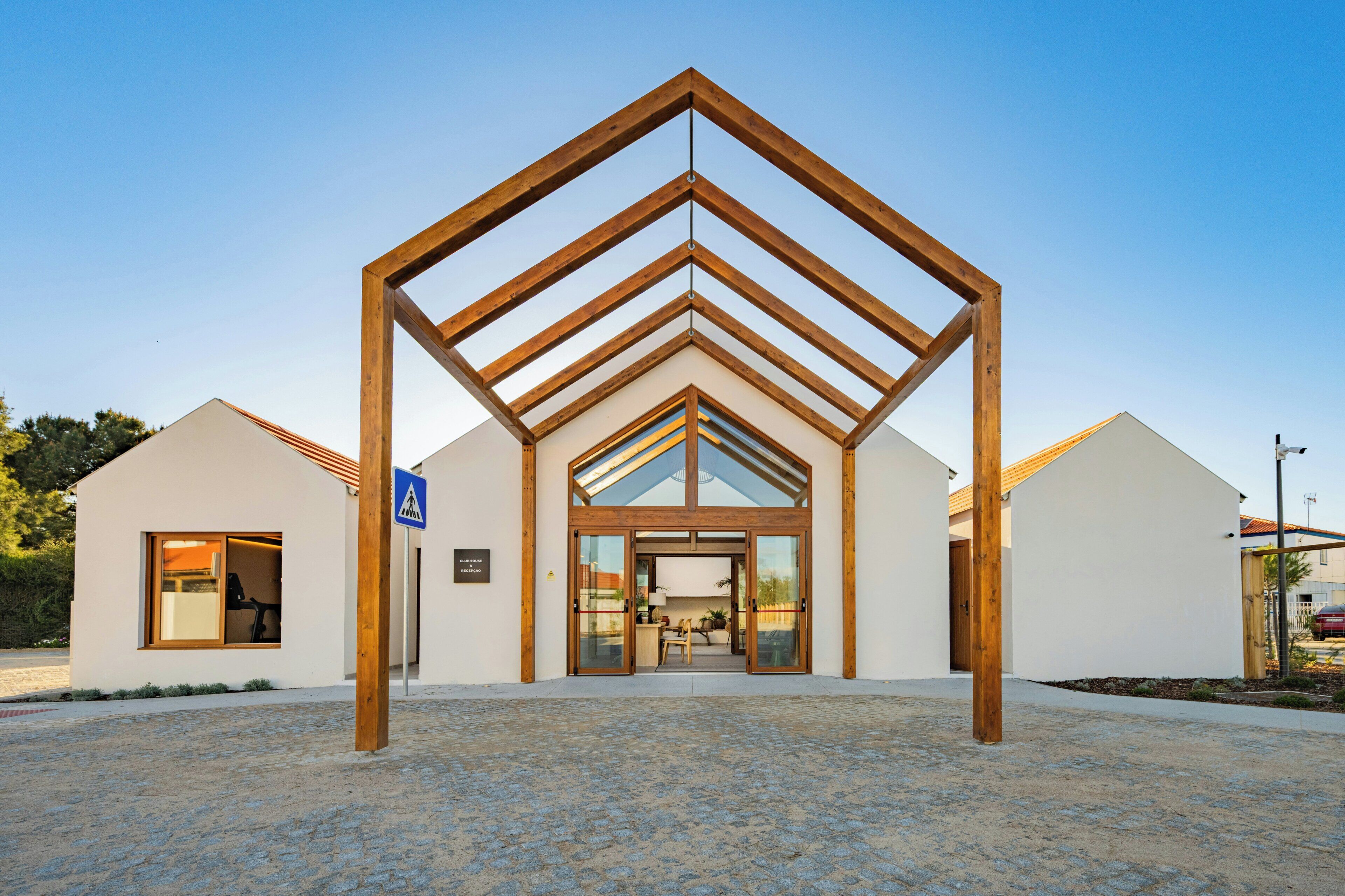 Ein modernes Gebäude mit auffälligem Eingang aus Holz, einem Empfangsbereich und blauem Himmel.