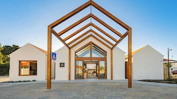 Ein modernes Gebäude mit auffälligem Eingang aus Holz, einem Empfangsbereich und blauem Himmel.