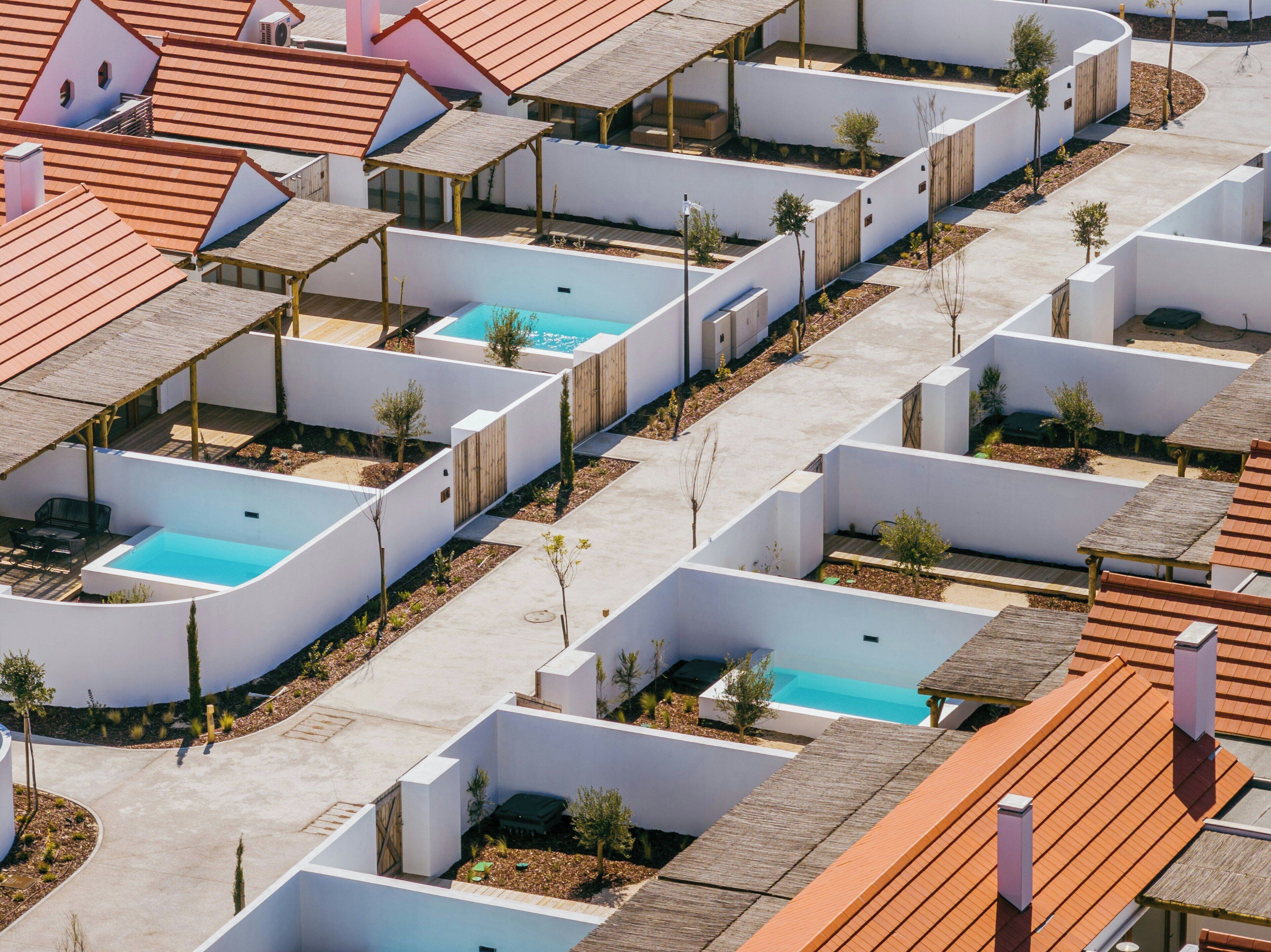 Et moderne boligkompleks med flere lejligheder, hvor hver har deres egen pool og terrasse.