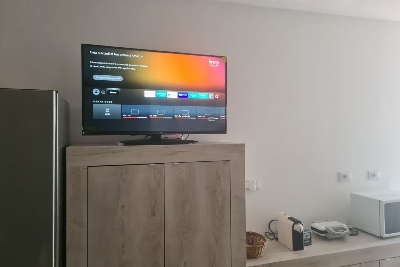 Een televisie op een houten kast, een digitale interface, een magnetron en een telefoon op een aanrecht.