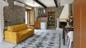A modern living room with a yellow sofa, a patterned rug, and a stone wall.
