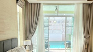 Habitación de hotel con una cama grande, ventilador de techo y vista al océano a través de un ventanal corredero.