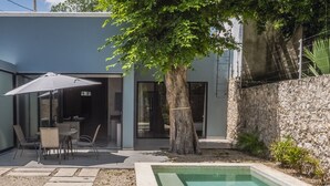 A modern outdoor patio with a pool, a dining area, and a tree providing shade. - Casa Péepen Merida Centro with Pool by LAHOS (Mérida)