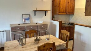 Una cocina con armarios de madera, una mesa de comedor con sillas y una lámpara colgante.
