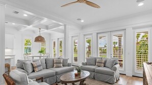 A spacious living room with a sectional sofa, a wooden coffee table, and a ceiling fan.