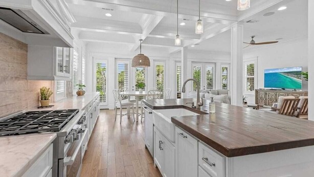 A spacious kitchen with a large island, white cabinetry, and a dining area with a table and chairs.