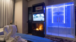 Habitación de hotel con chimenea, televisor y armario con puertas iluminadas.