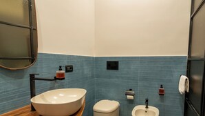 Un baño con un lavamanos ovalado grande, un inodoro y un bidé.