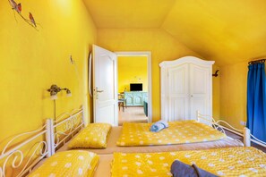 Une chambre avec deux lits, une armoire et une porte donnant sur une autre pièce.