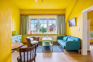 A bright yellow room with a window, a table, a sofa, and a chair. - Apartment '2' with Wi-Fi (Neuenkirchen)