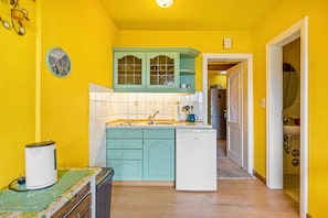 A kitchen with teal cabinets, a white sink, and a small refrigerator.