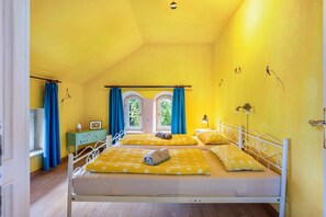 Een kamer met twee bedden, een raam met gordijnen, een nachtkastje en een wandlamp.