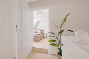 A bedroom with a bed, bedside table, lamp, and a potted plant.