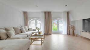 A modern living room with a sofa, coffee table, and TV stand. - Old Town Family Długa Living by Downtown Apartments (Gdańsk)