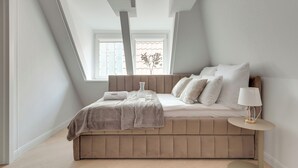 A bedroom with a bed, a bedside table, a window, and a lamp. - Old Town Family Długa Living by Downtown Apartments (Gdańsk)