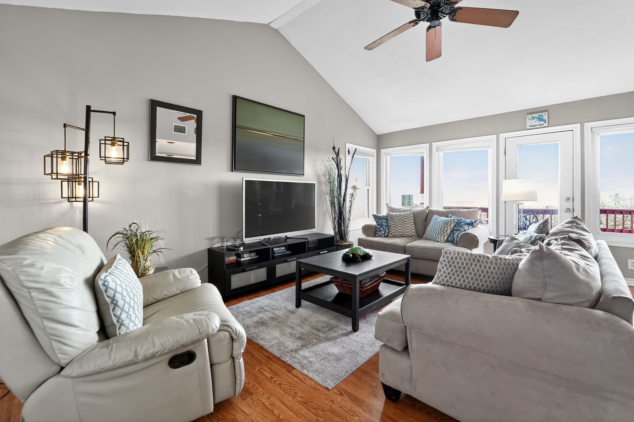 A modern living room with a flat-screen TV, two sofas, a coffee table, and a ceiling fan.