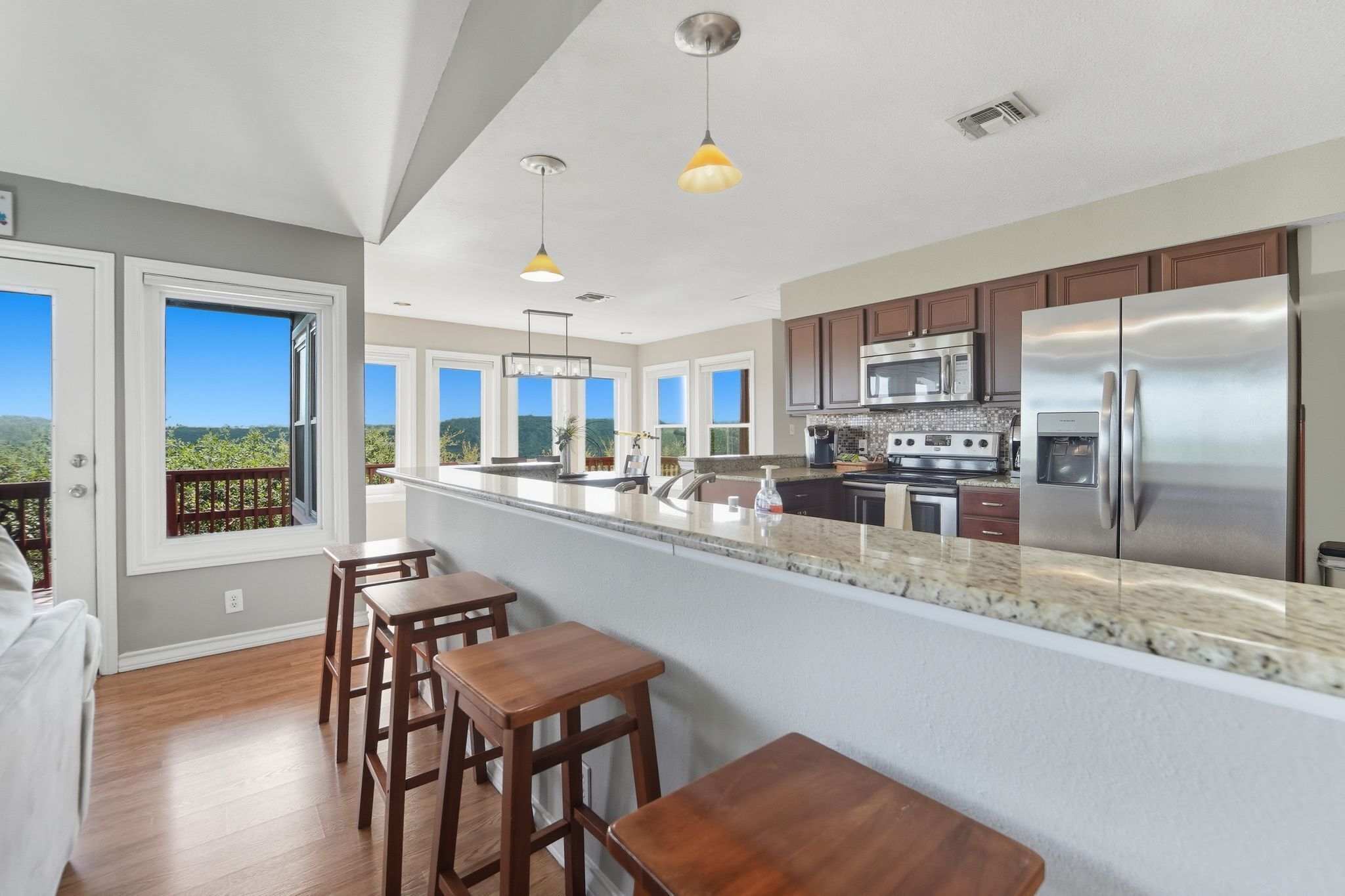 A modern kitchen with a large island, stainless steel appliances, and a view of the outdoors.