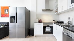 A modern kitchen with a stainless steel refrigerator, a built-in oven, a dishwasher, and white cabinetry. - Home2Book Relaxing Stay with Terrace & Pool (Puerto Santiago)