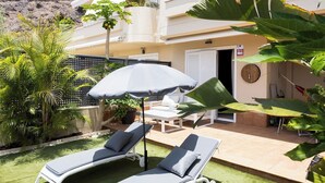 A villa with a patio, two lounge chairs, a table, and an umbrella. - Home2Book Relaxing Stay with Terrace & Pool (Puerto Santiago)