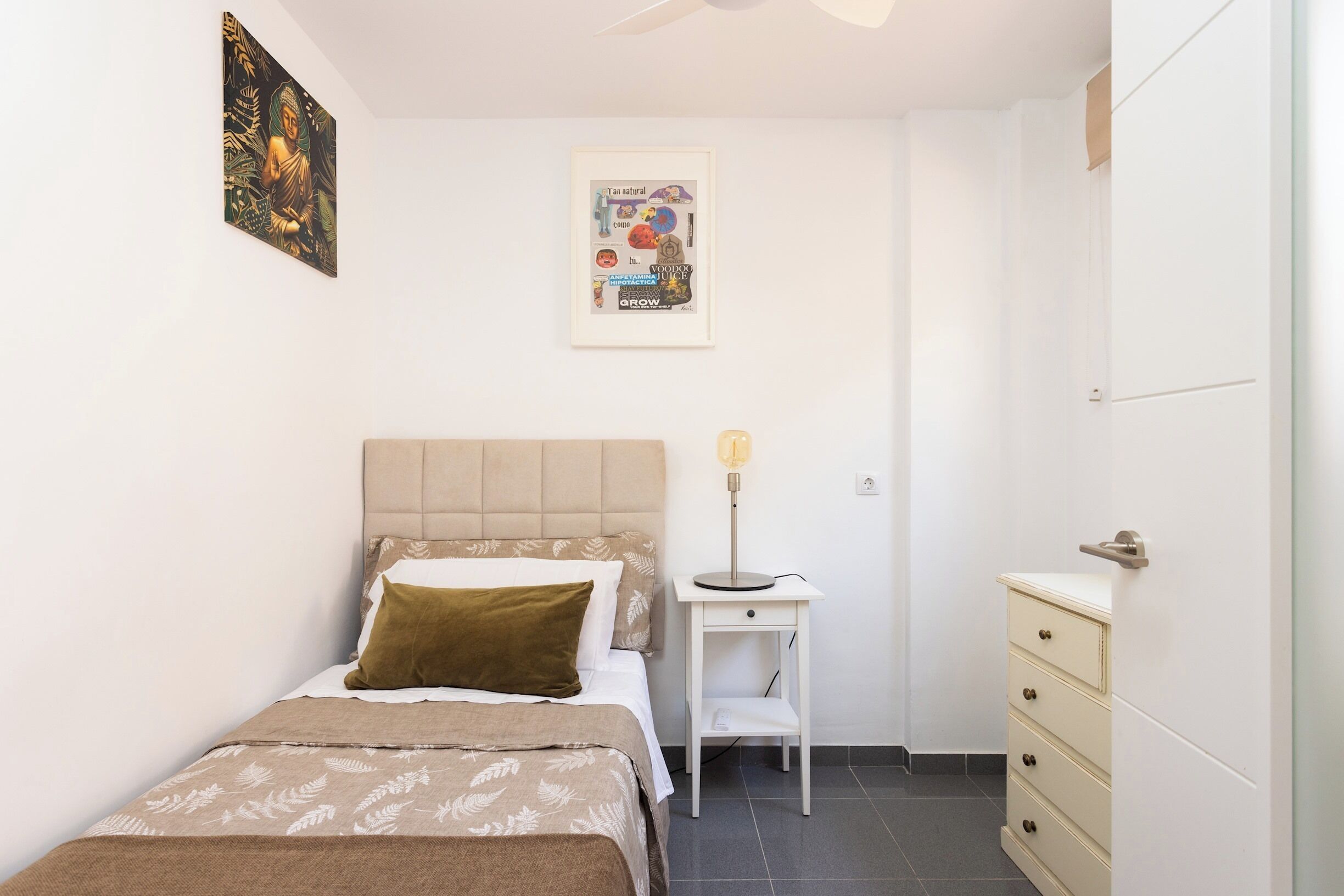 A bedroom with a bed, bedside table, lamp, and wardrobe.