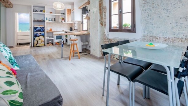 Eine moderne Küche mit Essbereich, Holzhockern und einem Glastisch.