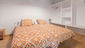 Ein Schlafzimmer mit einem großen Bett, weißen Wänden und einer eingebauten Regaleinheit.