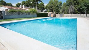 A rectangular swimming pool with clear blue water, surrounded by a concrete deck and a low brick wall. - Th01 Villa en Salou 4 Dorm 4 ba os Barbacoa (Salou)