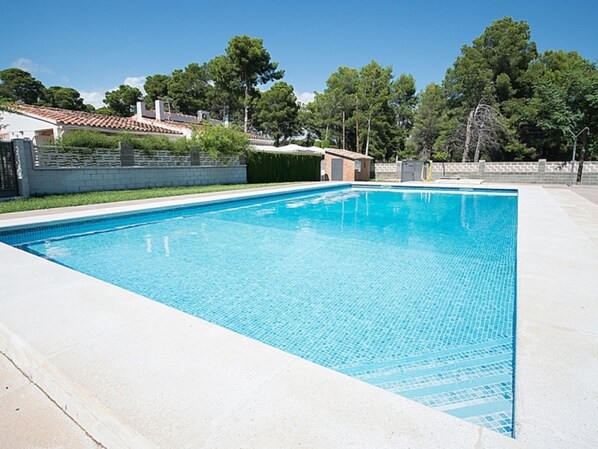 A rectangular swimming pool with clear blue water, surrounded by a concrete deck and a low brick wall. - Th01 Villa en Salou 4 Dorm 4 ba os Barbacoa (Salou)
