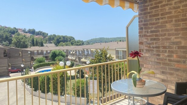 A balcony with a yellow and white striped awning, a round glass table, and a potted plant. - Th156 Casa Vacacional con Piscina en La Mora (Tarragona)