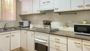 A kitchen with white cabinets, a microwave, a stove, and a sink. - Th156 Casa Vacacional con Piscina en La Mora (Tarragona)