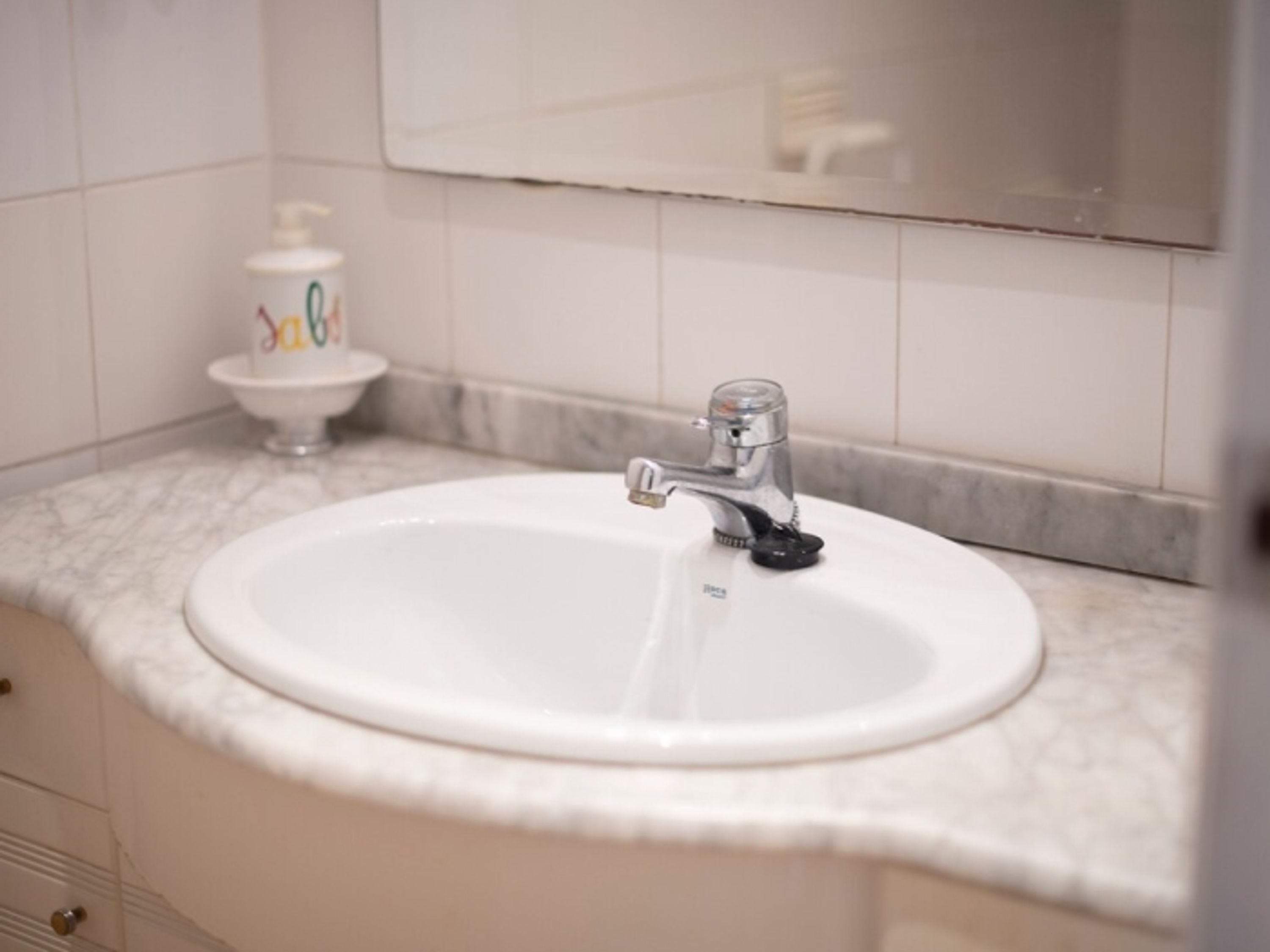 Een badkamer met een wit wastafel, een kraan en een spiegel erboven.