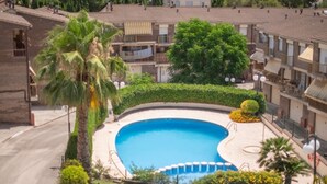 A residential area with a swimming pool surrounded by greenery and a multi-story building with balconies. - Th156 Casa Vacacional con Piscina en La Mora (Tarragona)