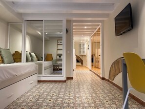 Une chambre à coucher avec un lit, un bureau et une chaise. Une porte coulissante donne accès à la salle de bain.