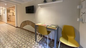 A modern living room with a patterned floor, a dining table with chairs, a flat-screen TV, and a shelf with decorative items. - Th143 Acogedor Estudio en Parte Alta (Tarragona)
