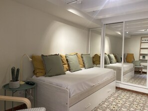 Un dormitorio con cama, mesita de noche, lámpara y un espejo grande.