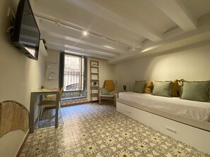 Una habitación con cama, escritorio, silla, televisor y ventana con vistas.