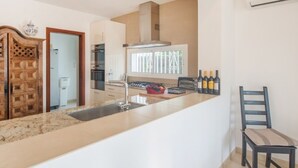 A modern kitchen with a central island, built-in oven, and a large window. - Th11 Villa in Cambrils con Piscina (Cambrils)