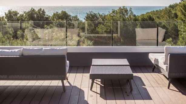 Een balkon met uitzicht op zee, voorzien van een bank en een tafel.