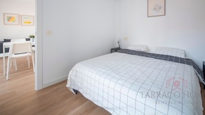 A bedroom with a bed, a desk, and chairs.