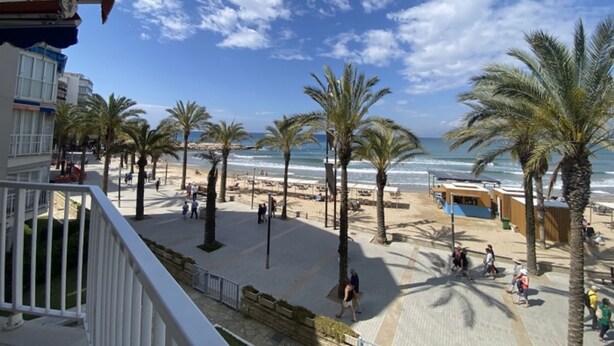 A beachside promenade with palm trees, beach umbrellas, and a pool area. - Th108 Apartamento con Acceso Directo a la Playa (Salou)