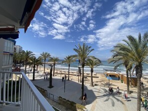 A beachside promenade with palm trees, beach umbrellas, and a pool area. - Th108 Apartamento con Acceso Directo a la Playa (Salou)