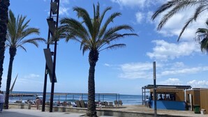 A beachside promenade with palm trees, a wooden structure, and a view of the ocean. - Th108 Apartamento con Acceso Directo a la Playa (Salou)