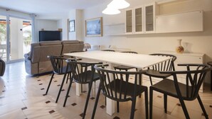 A modern kitchen with a dining table and chairs, a sofa, and a large window. - Th108 Apartamento con Acceso Directo a la Playa (Salou)