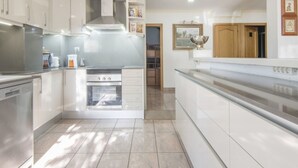 A modern kitchen with white cabinetry, stainless steel appliances, and a large island.