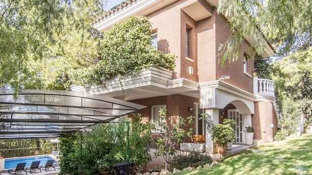 A two-story house with a covered patio and a swimming pool.
