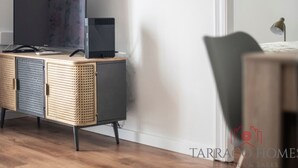 Une chambre moderne avec un meuble gris, un téléviseur et un petit haut-parleur.